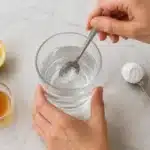 Half-teaspoon of baking soda being dissolved in a full glass of water